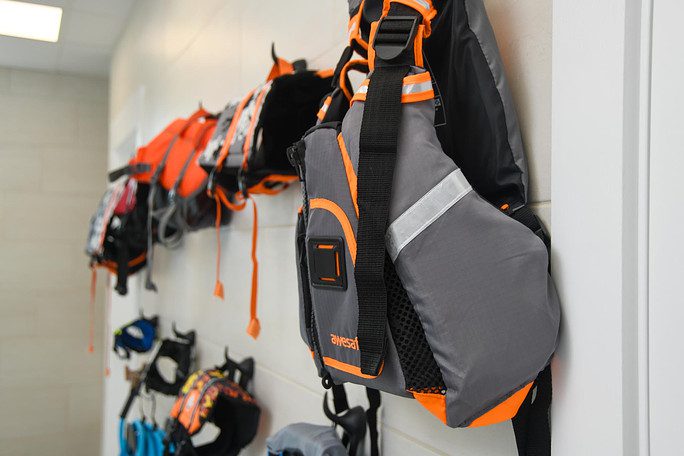 dog life jackets hanging on brick wall